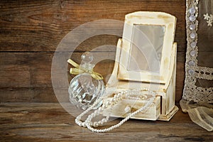 Vintage pearls , antique wooden jewelry box with mirror and perfume bottle on wooden table. filtered image