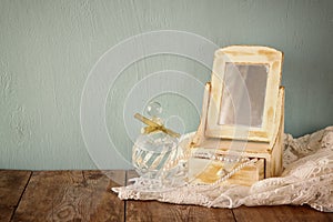 Vintage pearls , antique wooden jewelry box with mirror and perfume bottle on wooden table. filtered image