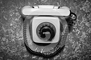 Vintage phone with a rotational dial on a concrete surface.