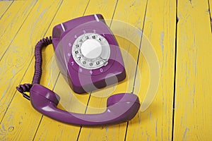 Vintage Phones - Purple retro phone is picked up yellow background