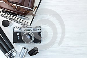 vintage photo camera with equipments on white wooden board background flat view
