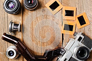 vintage photo camera and lenses, negatives and slides on a textured wooden table. View from above. retro style. Space for text