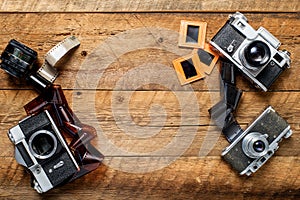 vintage photo cameras, negatives and slides on a textured wooden table. View from above. retro style. Space for text