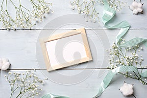 Vintage photo frame with flowers on light blue wooden background. Banner mockup for congratulation with womans or mother day, wedd