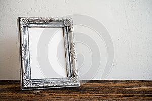 Vintage photo frame on old wooden table over white wall background