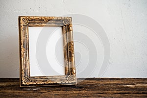 Vintage photo frame on old wooden table over white wall background