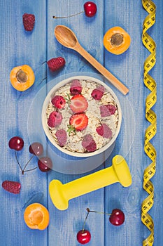 Vintage photo, Fresh prepared oatmeal with fruits, centimeter and dumbbells, healthy lifestyle and nutrition