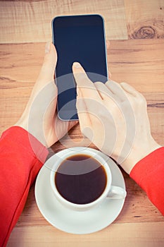 Vintage photo, Hand of woman touching blank screen of mobile phone, cup of coffee