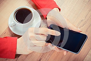 Vintage photo, Hand of woman touching screen of mobile phone or smartphone, cup of coffee