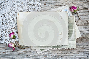 Vintage photo, lace fabric and dry tea roses on the old wood