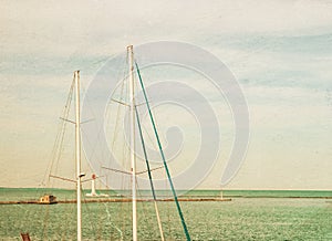 Vintage photo of lighthouse tower and ship masts.