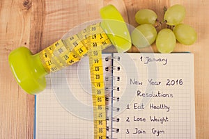 Vintage photo, New years resolutions written in notebook and dumbbells with centimeter