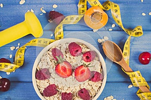 Vintage photo, Oatmeal with fruits, tape measure and dumbbells, concept of slimming, sporty lifestyle and healthy nutrition