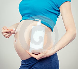 Vintage photo, Pregnant woman applying moisturizing lotion on belly, avoid stretch marks