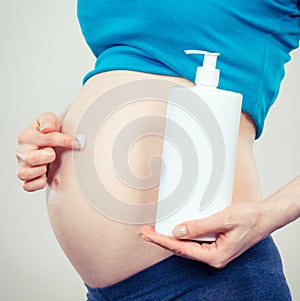 Vintage photo, Pregnant woman applying moisturizing lotion on belly, avoid stretch marks