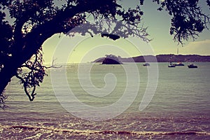 Vintage photo of a view over Bay of Islands. Leisure boats anchored in tranquil azure water near Paihia, New Zealand