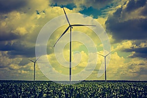 Vintage photo of windmills standing on corn field