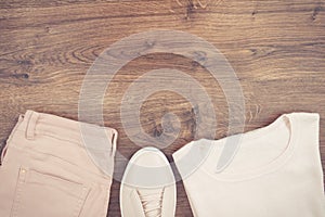 Vintage photo, womanly pink leather shoes, pants and sweater on rustic boards, copy space for text