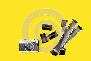 Vintage photographic camera and film negatives on a yellow background
