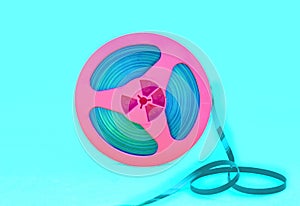 Vintage pink audio reel with recording tape on green background. Trendy pop art style.