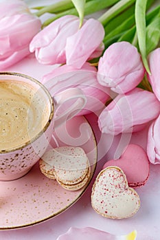 Vintage pink coffee cup, tulip flowers and french sweet cookies macarons macaroons on marble background