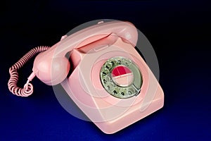 Vintage Pink Telephone on a Blue Table Surface