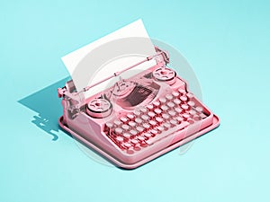 Vintage pink typewriter on blue background with space for text