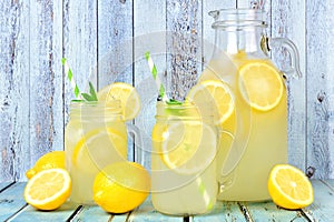 Vintage pitcher of lemonade with mason jar glasses on rustic blue wood