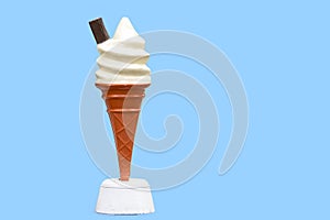 Vintage plastic promotional UK ice cream cone with vanilla whipped ice cream and a chocolate flake with a blue background in UK