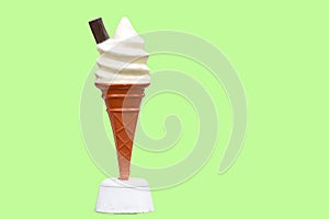 Vintage plastic promotional UK ice cream cone with vanilla whipped ice cream and a chocolate flake with a green background in UK