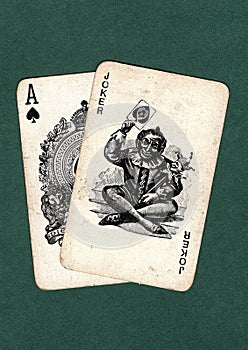 Vintage playing cards showing an ace of spades and a joker.