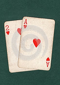 Vintage playing cards showing an ace and two of hearts.