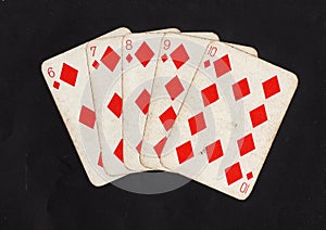 Vintage playing cards showing a five card run of diamonds.