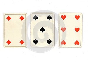 Vintage playing cards showing a three card in different suits.