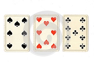 Vintage playing cards showing a three card in different suits.