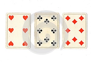 Vintage playing cards showing a three card in different suits.