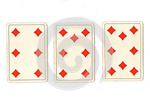 Vintage playing cards showing a three card run of diamonds.