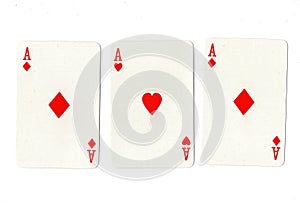 Vintage playing cards showing three red aces.