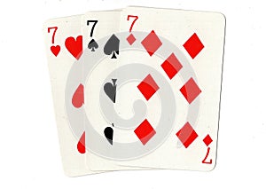 Vintage playing cards showing three sevens.