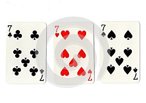 Vintage playing cards showing three sevens.