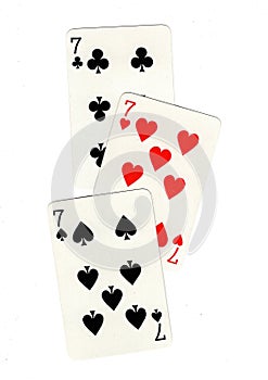 Vintage playing cards showing three sevens.