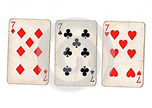 Vintage playing cards showing three sevens.