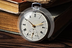 Vintage pocket watch on the background of old books