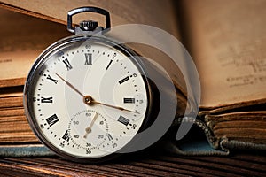Vintage pocket watch on the background of old books