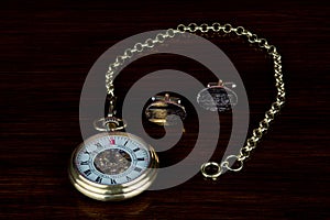 Vintage Pocket Watch and Chain with Gold Cuff Links on a Wooden Table Top