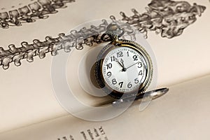 Vintage pocket watch close up with an opened book on the background