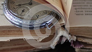 Vintage pocket watch next to the old faded book,