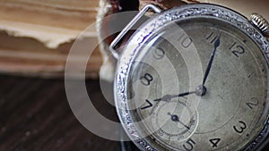 Vintage pocket watch next to the old faded book,