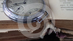 Vintage pocket watch next to the old faded book,