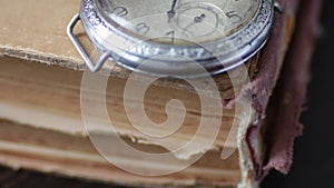 Vintage pocket watch next to the old faded book,